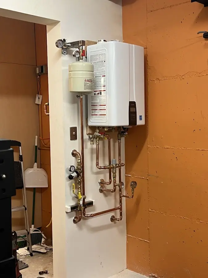 Plumbing technician inspecting water heater connections in Thomaston